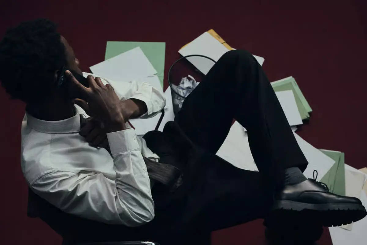 A business owner surrounded by paperwork, mid-phone-call